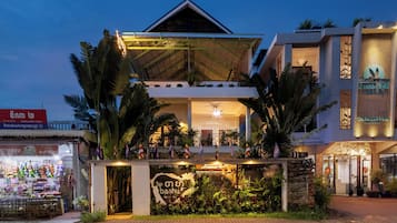 A hotel with a prominent balcony and a sign with Thai script.