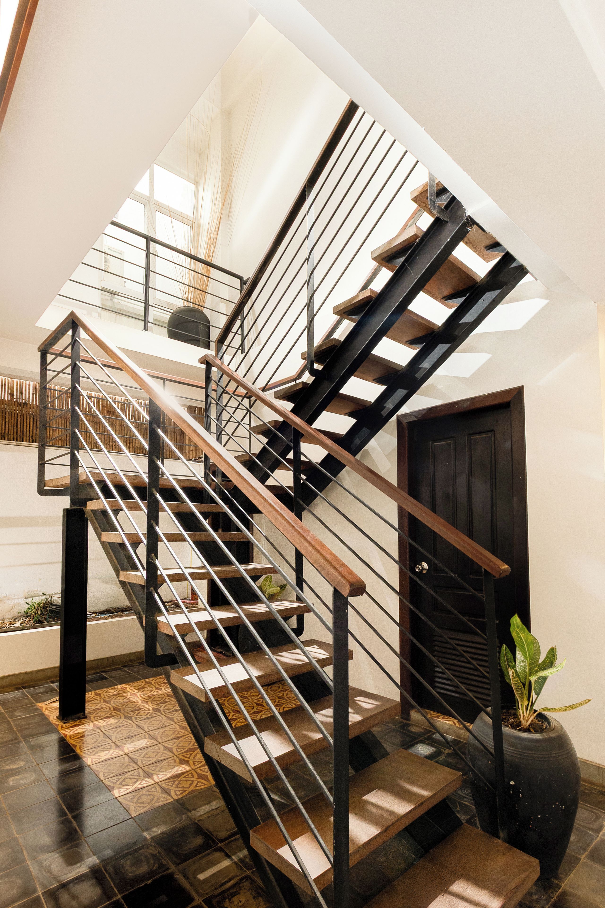 A modern staircase with a wooden handrail and metal balusters, leading to an upper floor.