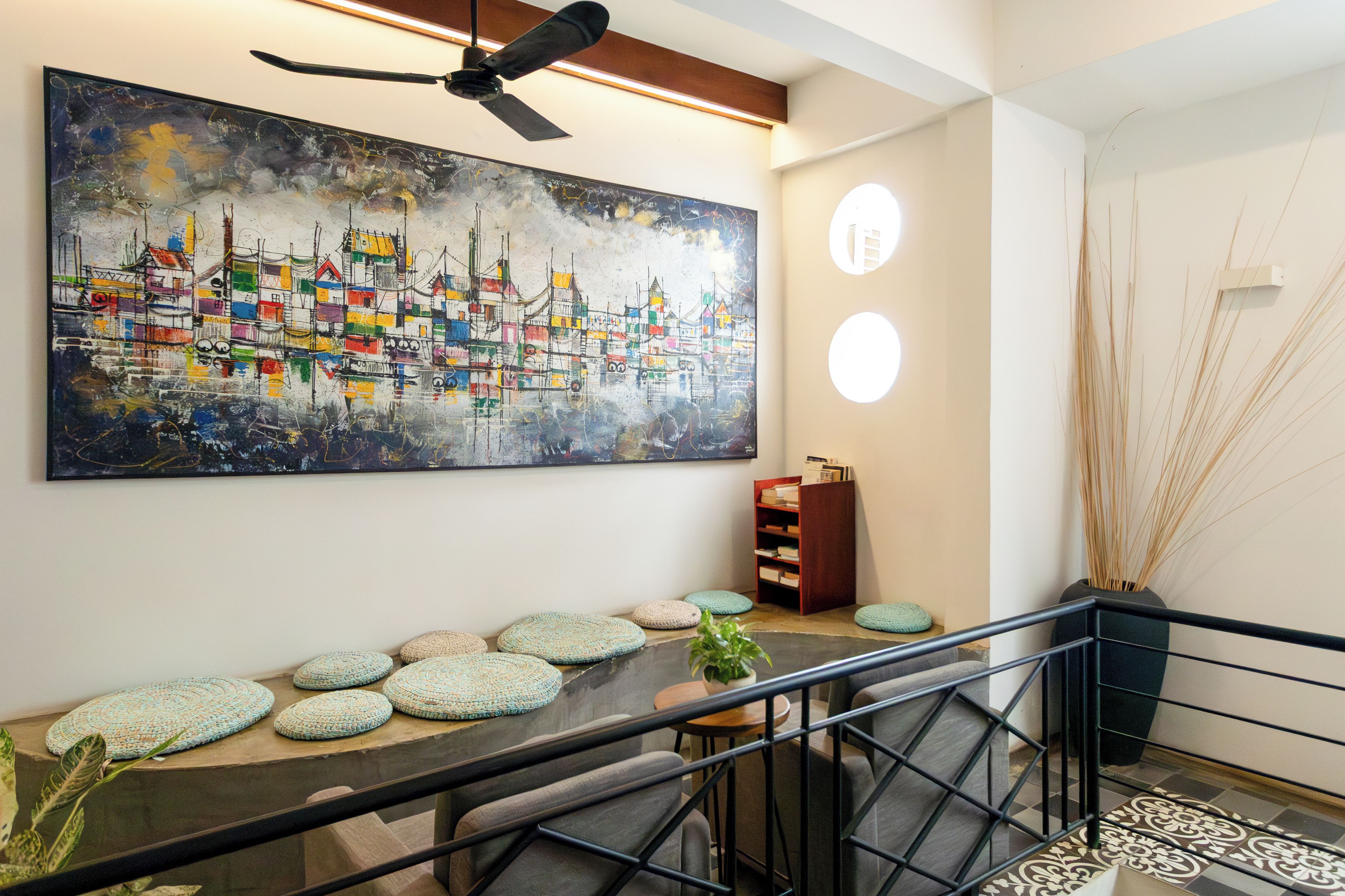 A modern interior with a large abstract painting, a staircase with a railing, and a wooden bookshelf.