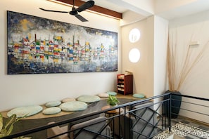A modern interior with a large abstract painting, a staircase with a railing, and a wooden bookshelf. - Home-like Family/Group Stay in Three-Bedroom Suite- Near Pubstreet, Old Market (Krong Siem Reap)