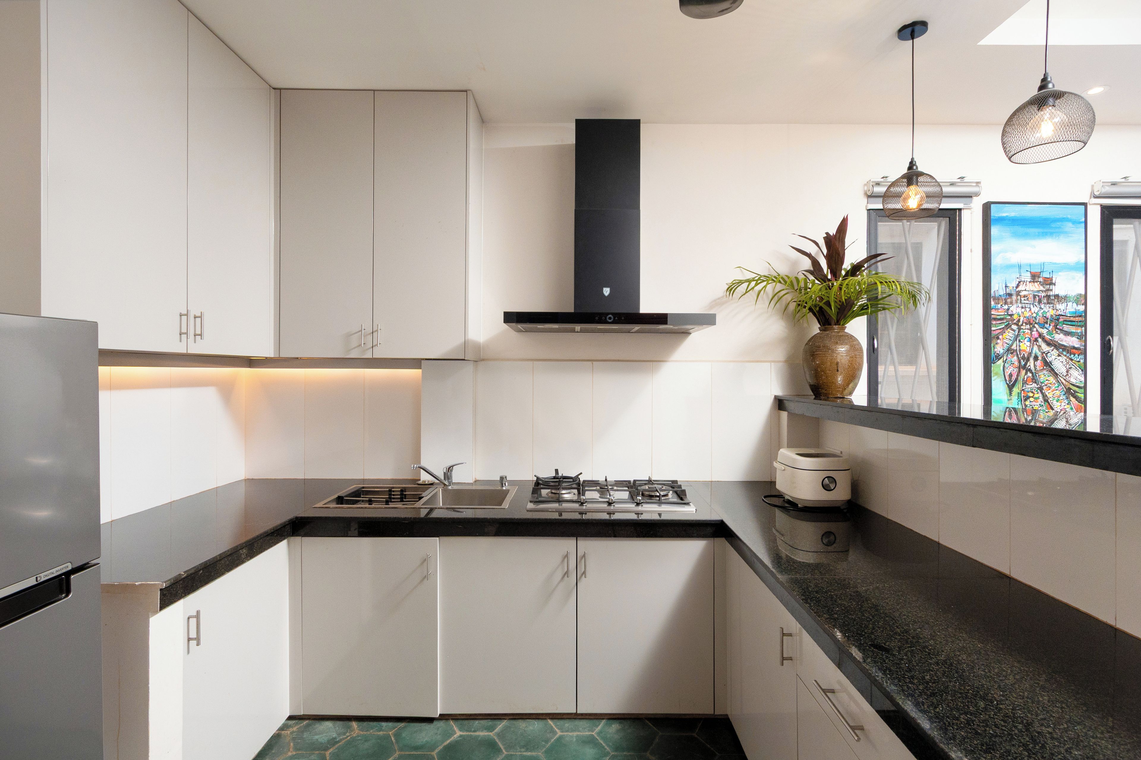 A modern kitchen with white cabinets, a black countertop, a gas stove, and a stainless steel refrigerator.