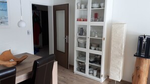 Un comedor con mesa y sillas de madera, un armario con vajilla y una puerta que da a otra habitación.