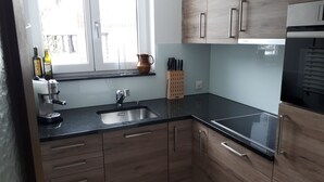 Una cocina moderna con armarios de madera, encimera negra, pileta de acero inoxidable y horno empotrado.