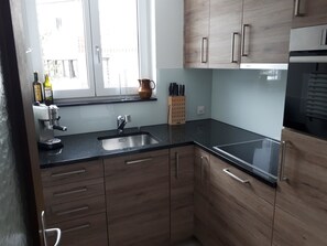 Een koelkast, een vaatwasser, kookgerei, borden en bestek