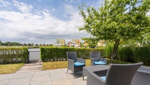 Eine Terrassengruppe im Freien mit Korbmöbeln und Blick auf Wohnhäuser.