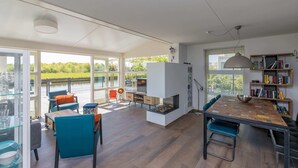 A spacious living area with a fireplace, a dining table, and a bookshelf.