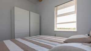 A bedroom with a bed, a window, and a wardrobe.