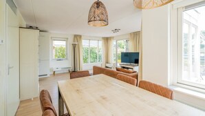 Un vaste espace de vie comprenant une grande table en bois, des canapés en cuir et un téléviseur.
