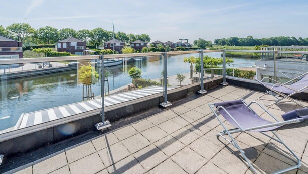 Une terrasse sur le toit avec une rambarde en verre, une piscine et des chaises longues.