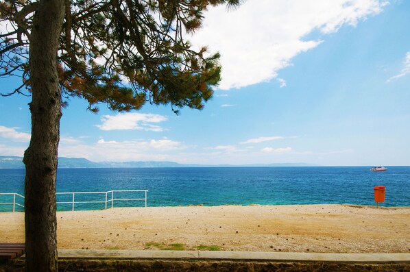 A beach with a clear view of the sea, a distant boat, and a red trash bin. - Beautiful villa with sea view, for 7 people (Ripenda)