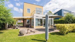 A modern house with a patio, a barbecue grill, and a covered seating area. - Beautiful home with roof terrace and a view of the water. (Oude-Tonge)