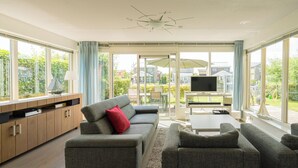 A modern living room with a sofa set, a TV, and a dining area with a table and chairs. - Beautiful home with roof terrace and a view of the water. (Oude-Tonge)