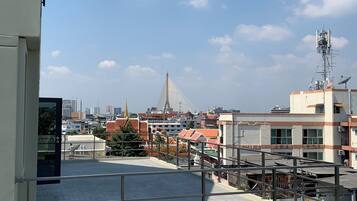 A rooftop terrace with a view of a cityscape, including a distinctive bridge and modern buildings.