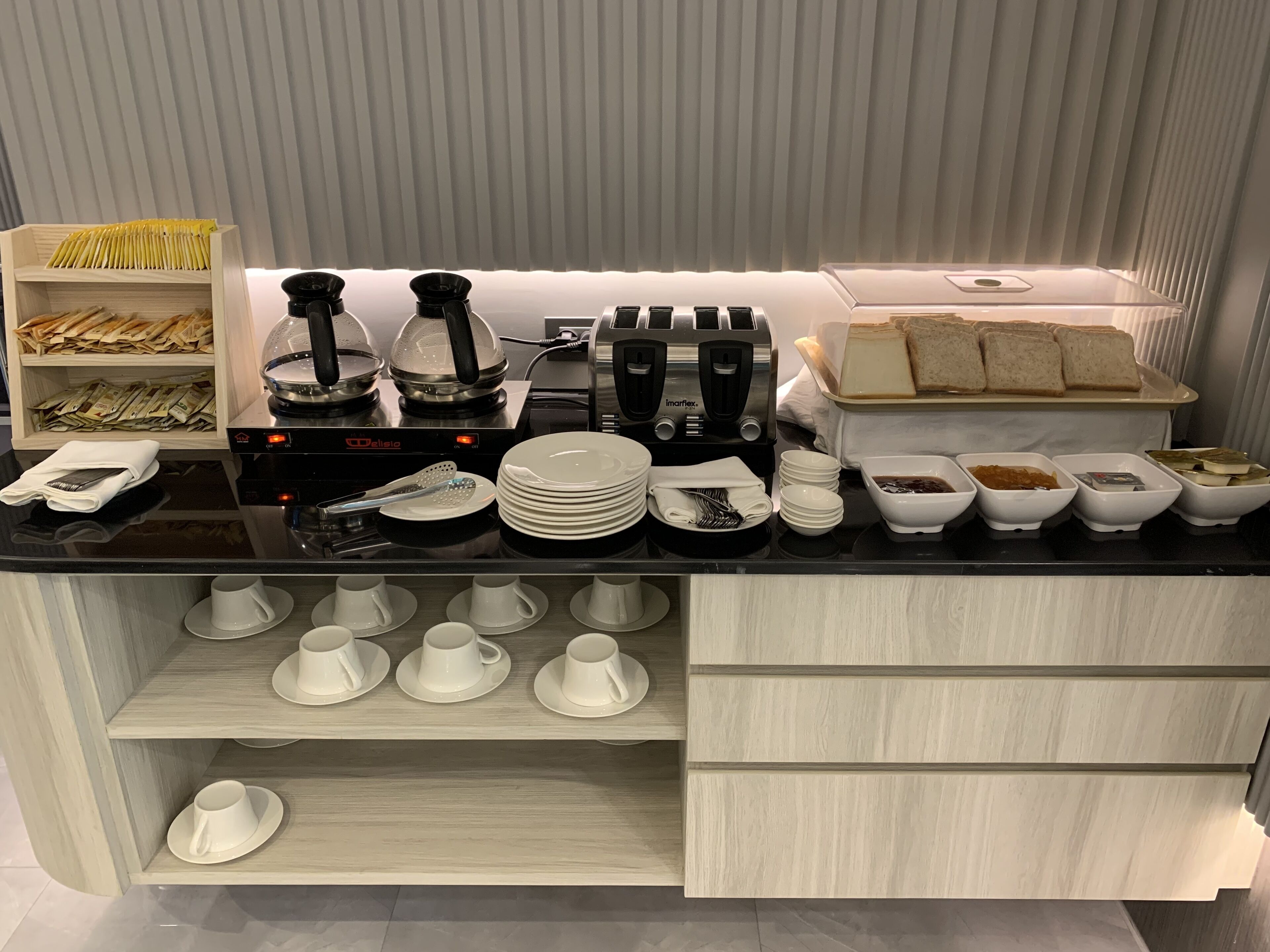 Un buffet de petit-déjeuner proposant une variété d'aliments, de couverts et une machine à café.