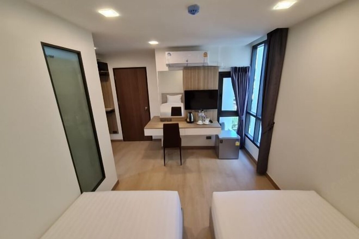 A compact hotel room with a kitchenette, a single bed, a desk, and a TV.