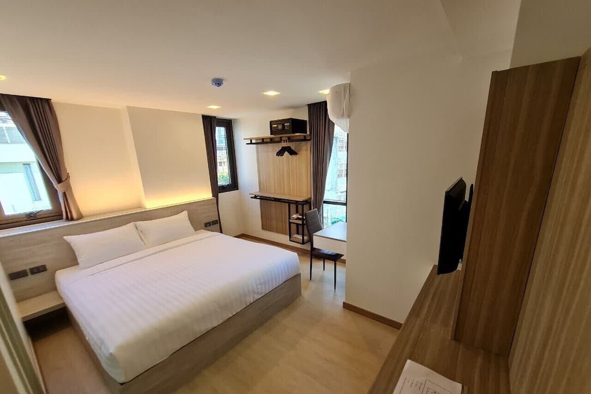 A modern hotel room with a large bed, a desk, and a chair.