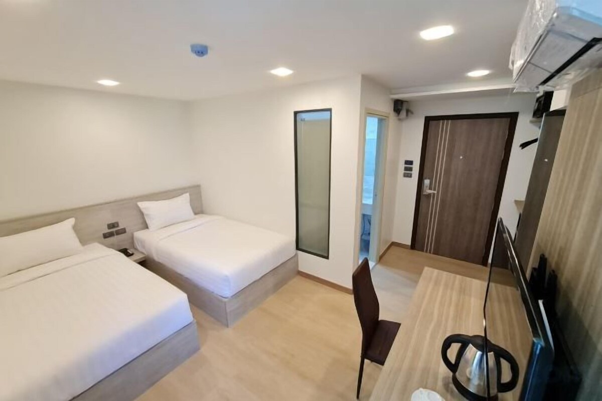 A hotel room with two beds, a desk, and a chair.