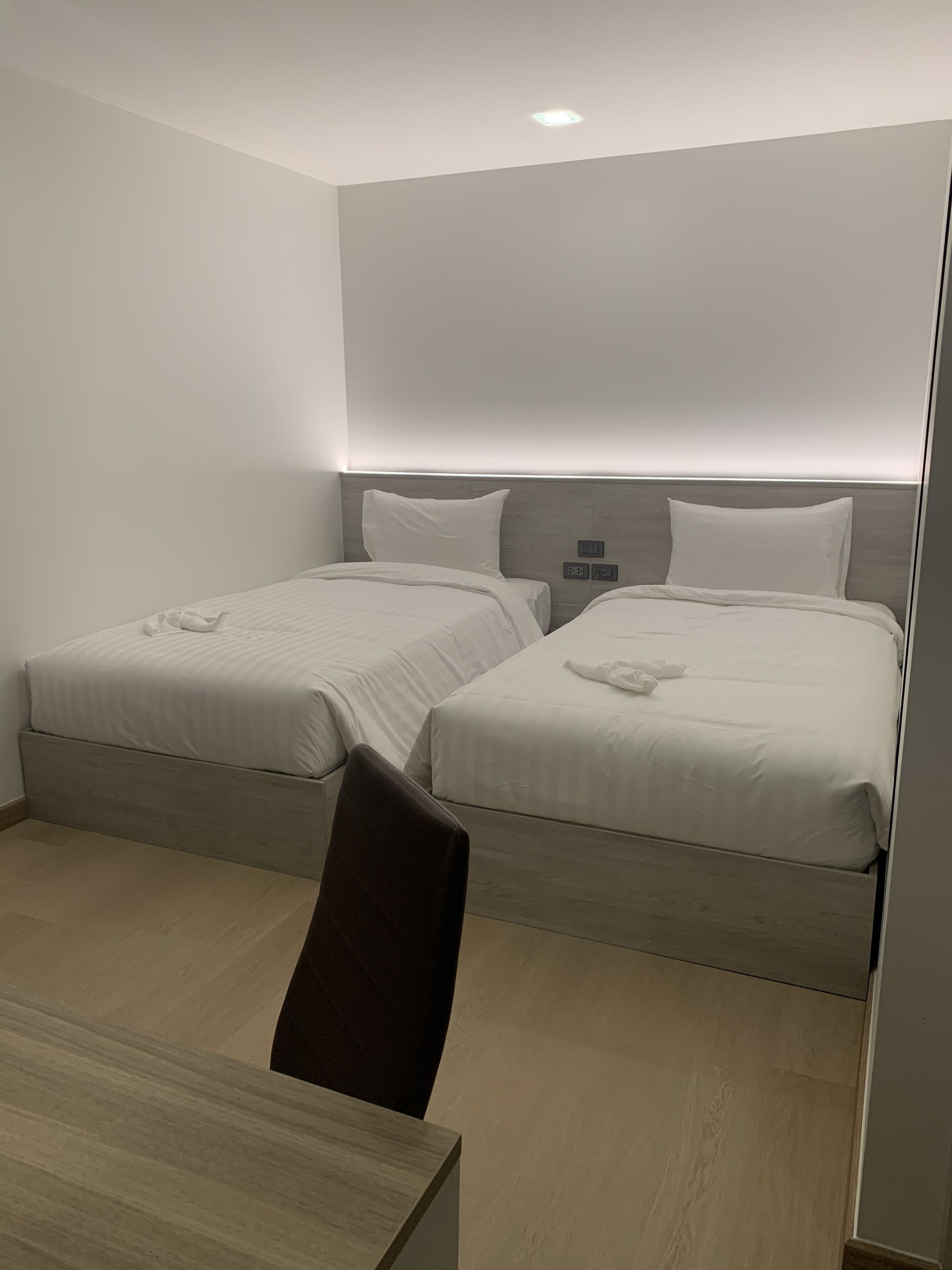 Een hotelkamer met twee bedden, een bureau en een stoel.