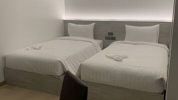 Een hotelkamer met twee bedden, een bureau en een stoel.