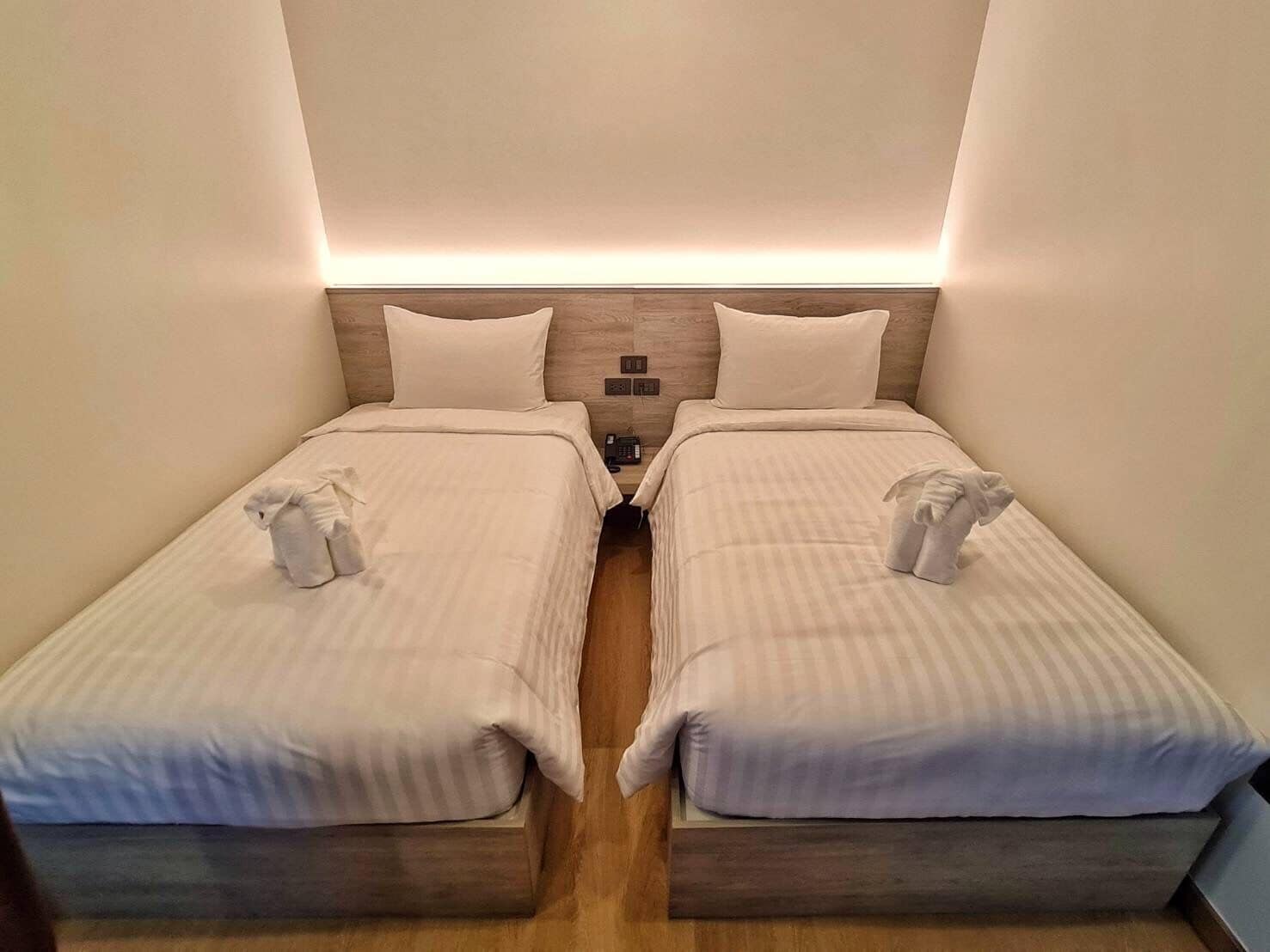 A twin room with two single beds, each with a pillow and a towel.