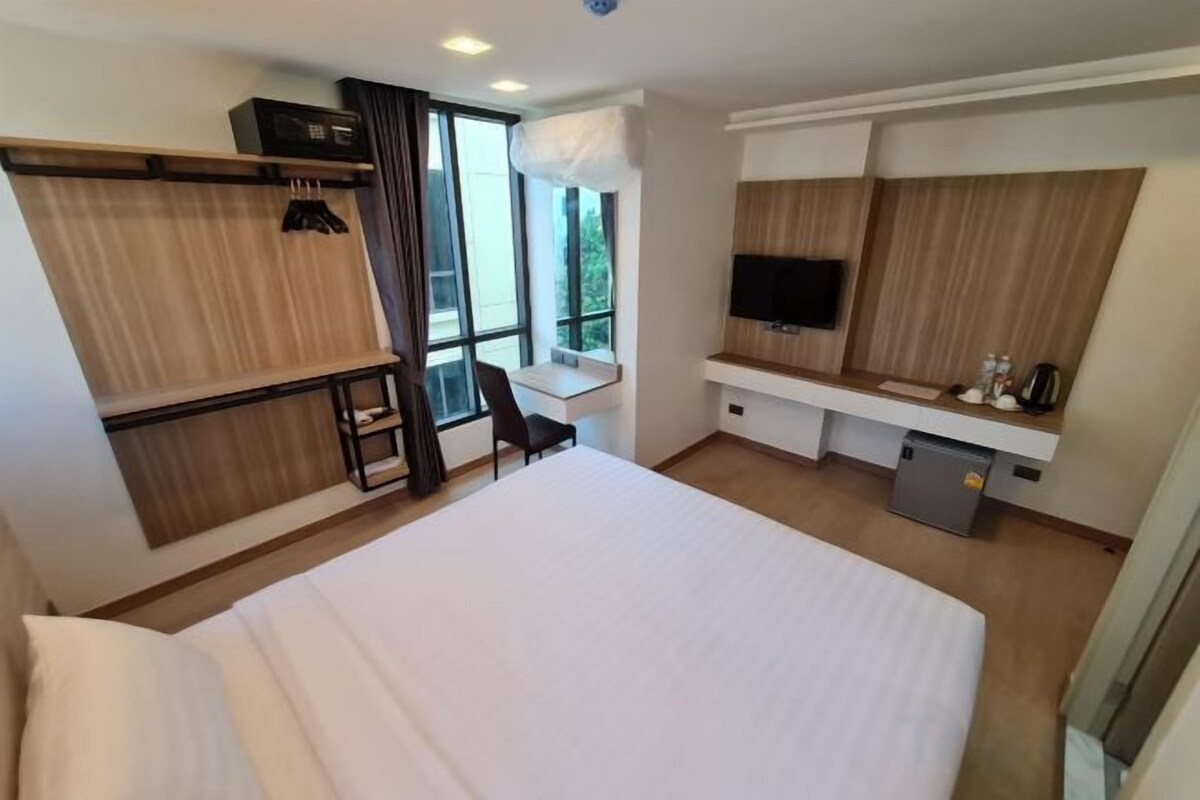 A hotel room with a large bed, a desk, a TV, and a window with a view.