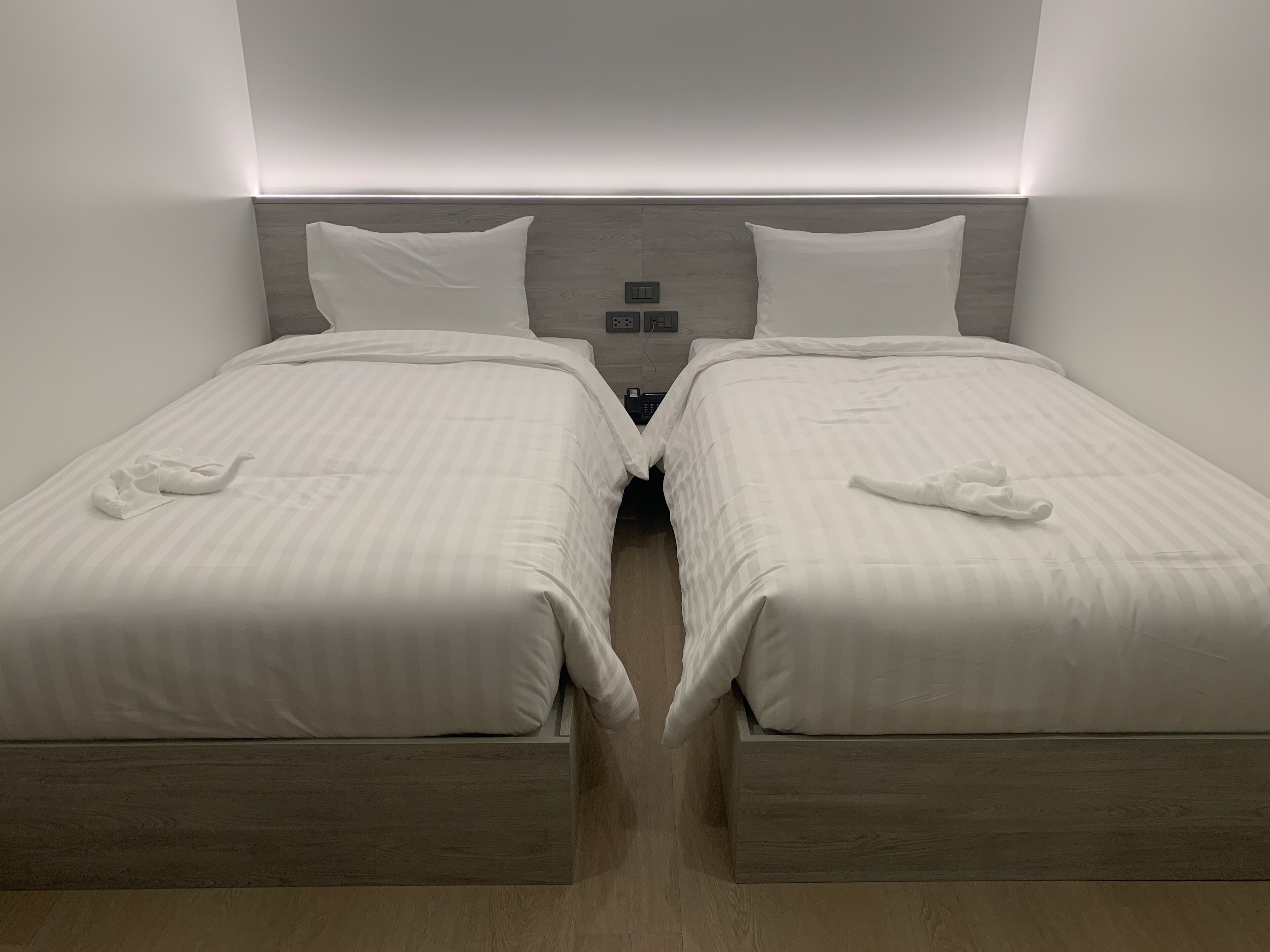 A hotel room with two beds, each with a pillow and a towel.