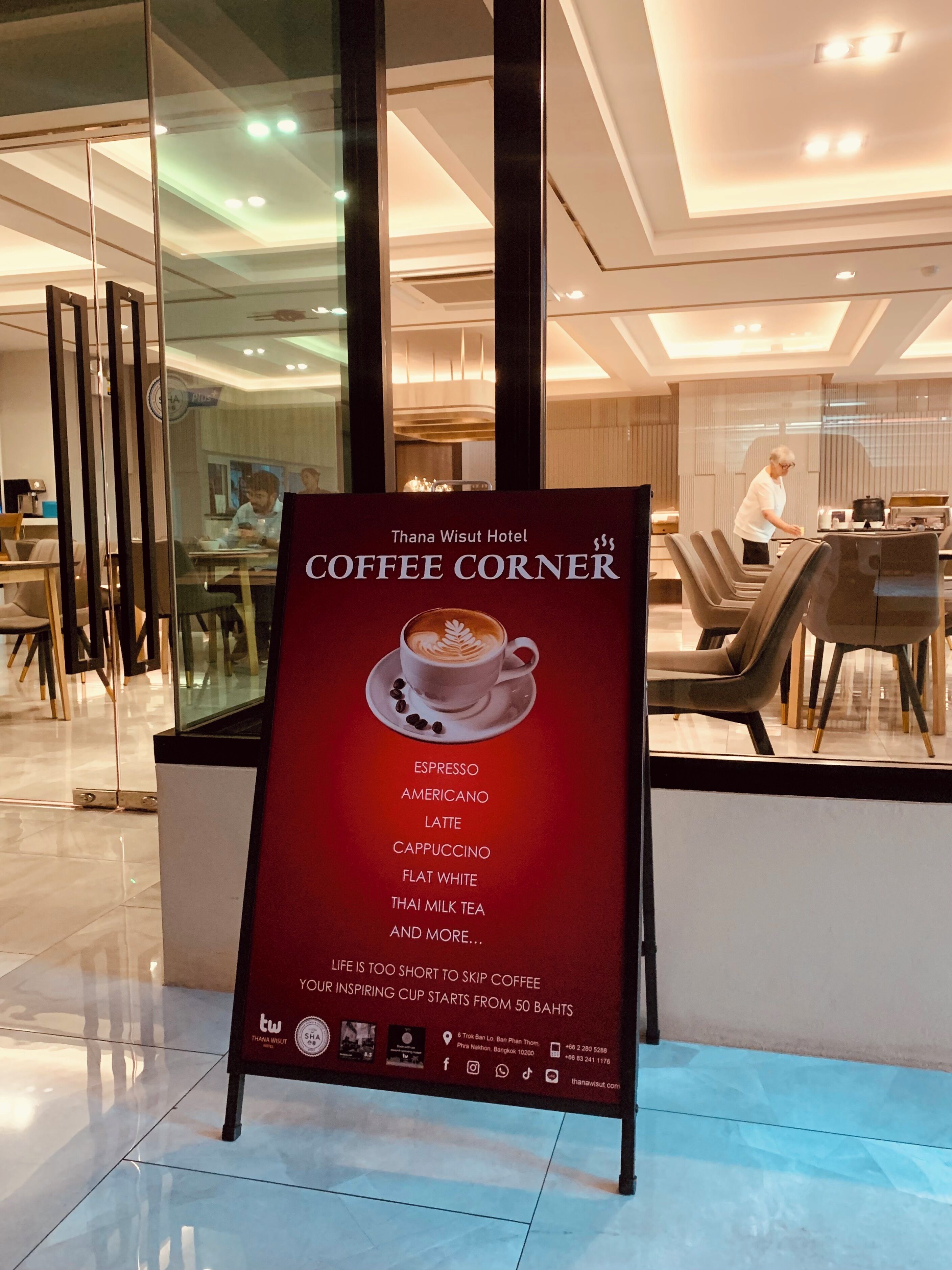 A hotel interior with a coffee corner sign listing various coffee types.