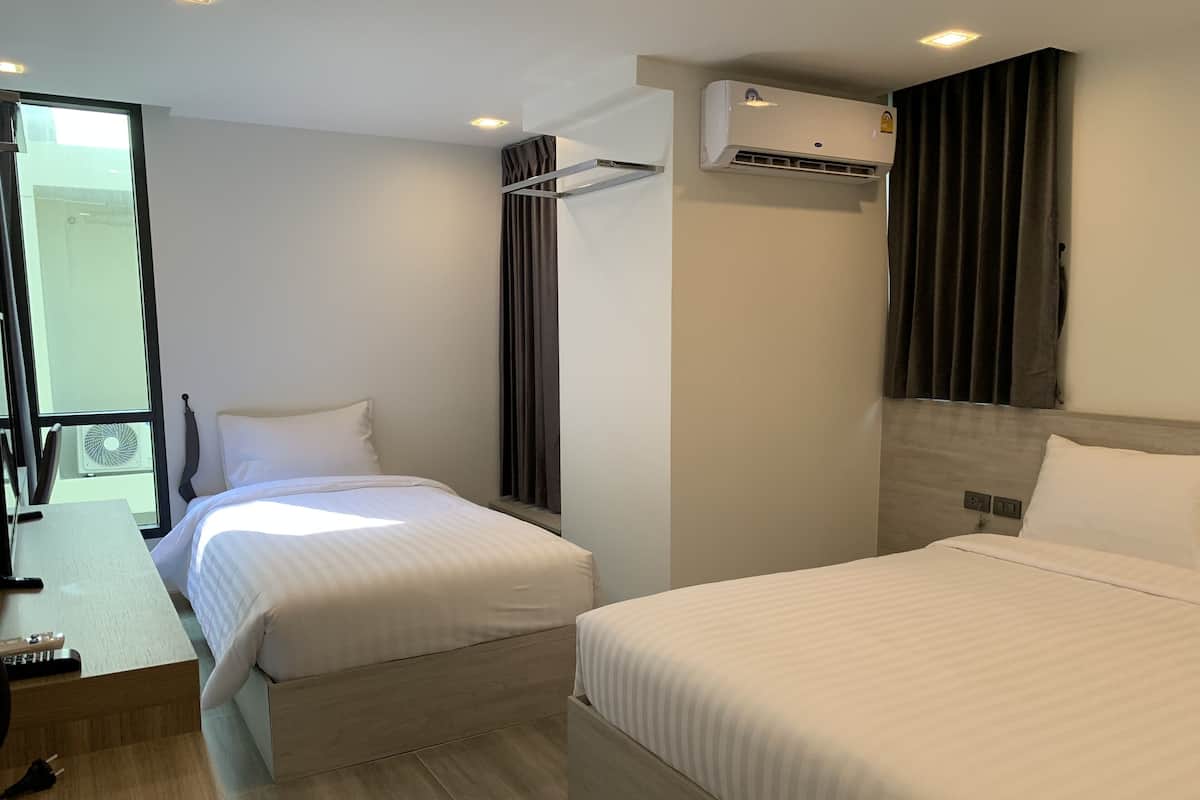 A modern hotel room with two beds, a desk, and a large window.