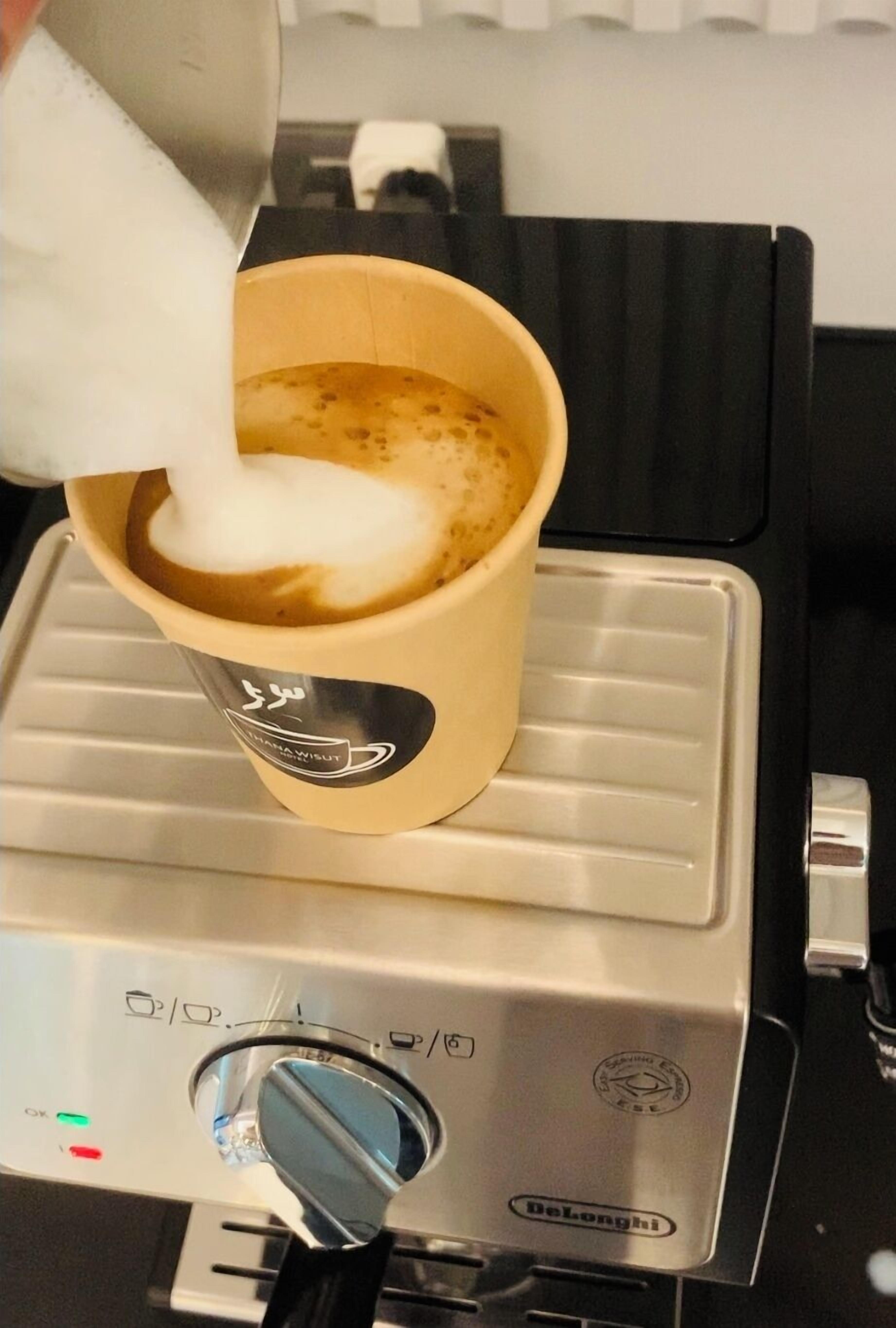 A coffee machine dispensing milk into a cup.
