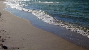 A beach with footprints leading to the water, a clear sky, and gentle waves. - Domki na wodzie ARKA 1, rower wodny, do morza oraz centrum 400m (Mielno)