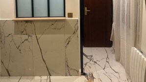 Une salle de bain moderne avec un meuble-lavabo en marbre, une fenêtre en verre dépoli et une porte en bois.