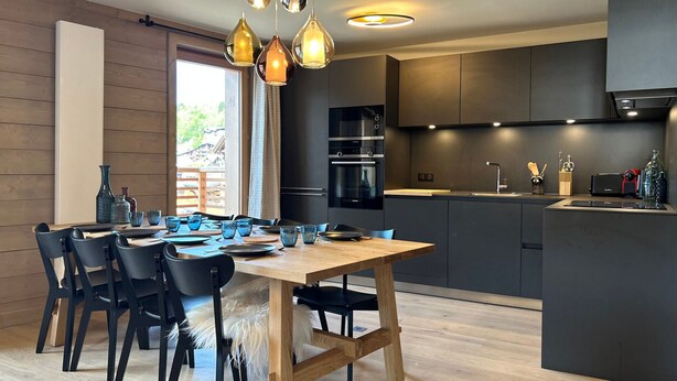 Een moderne keuken met donkere kastjes, een centraal eiland en hanglampen.