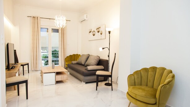 Un salon moderne avec un canapé, un fauteuil jaune, une table basse et un téléviseur.