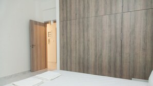 Une chambre à coucher avec un lit, une armoire en bois et une porte donnant sur une autre pièce.