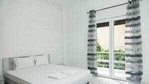 Une chambre à coucher avec un lit, une fenêtre avec des rideaux et une vue sur la verdure à l’extérieur.