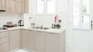 Une cuisine moderne avec des meubles blancs, un évier en acier inoxydable et une fenêtre au-dessus du plan de travail.