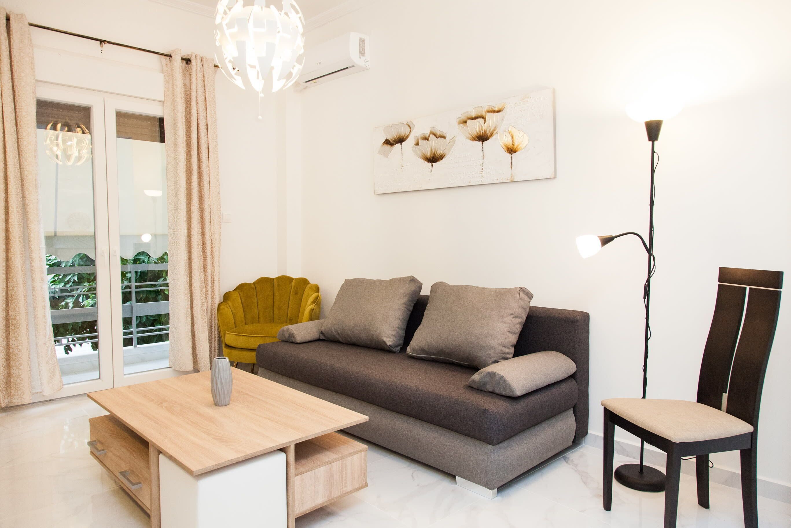 A modern living room with a sofa, a wooden table, a chair, and a floor lamp.