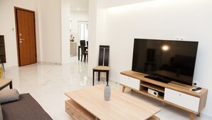 Un salon moderne avec un téléviseur à écran plat, une table basse en bois et un canapé.