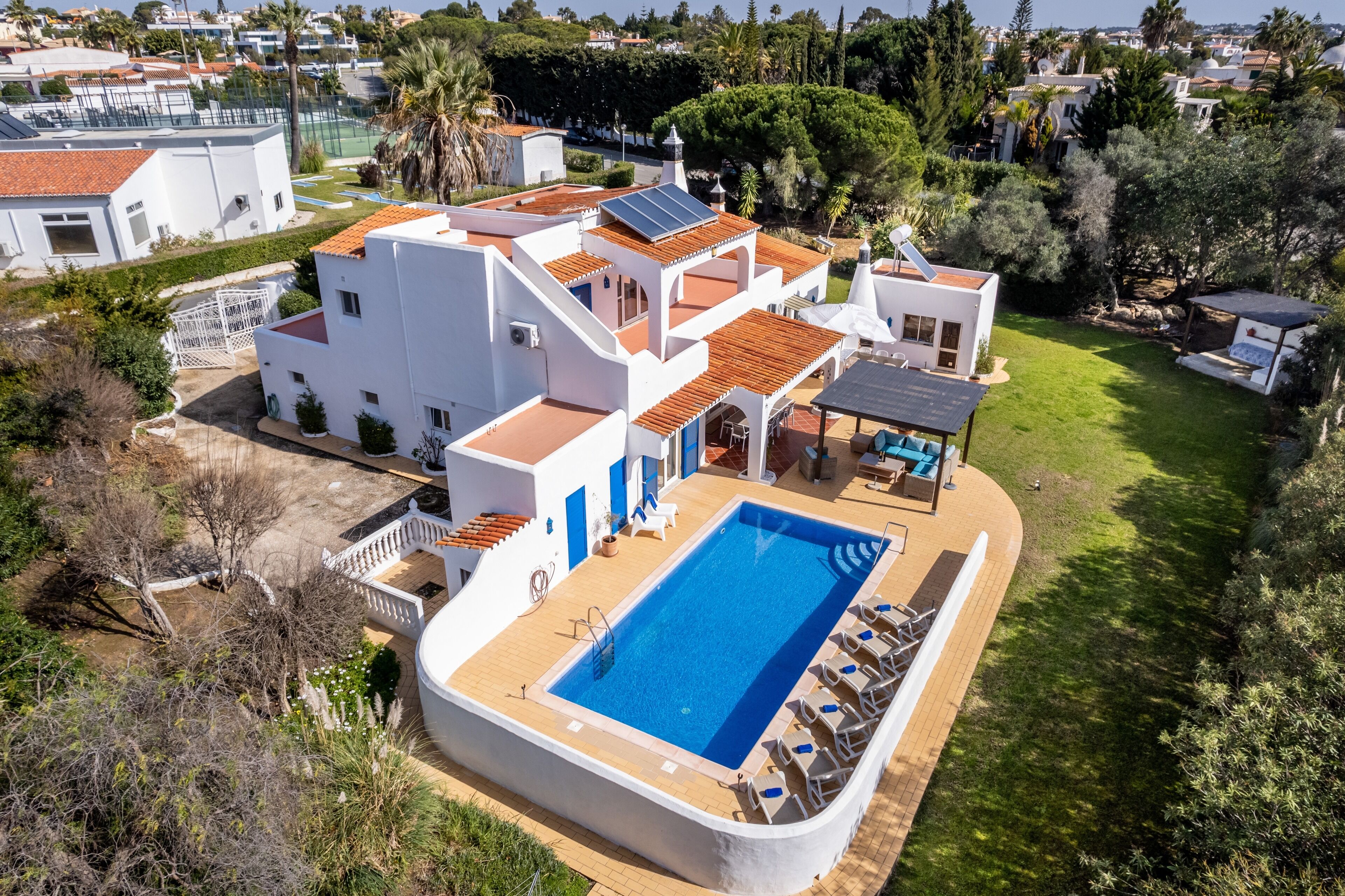 Una villa moderna con piscina, paneles solares y un jardín bien cuidado.