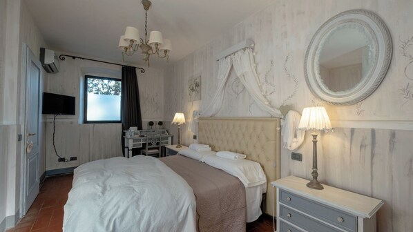 A bedroom with a large bed, a vanity with a mirror, and a chandelier.