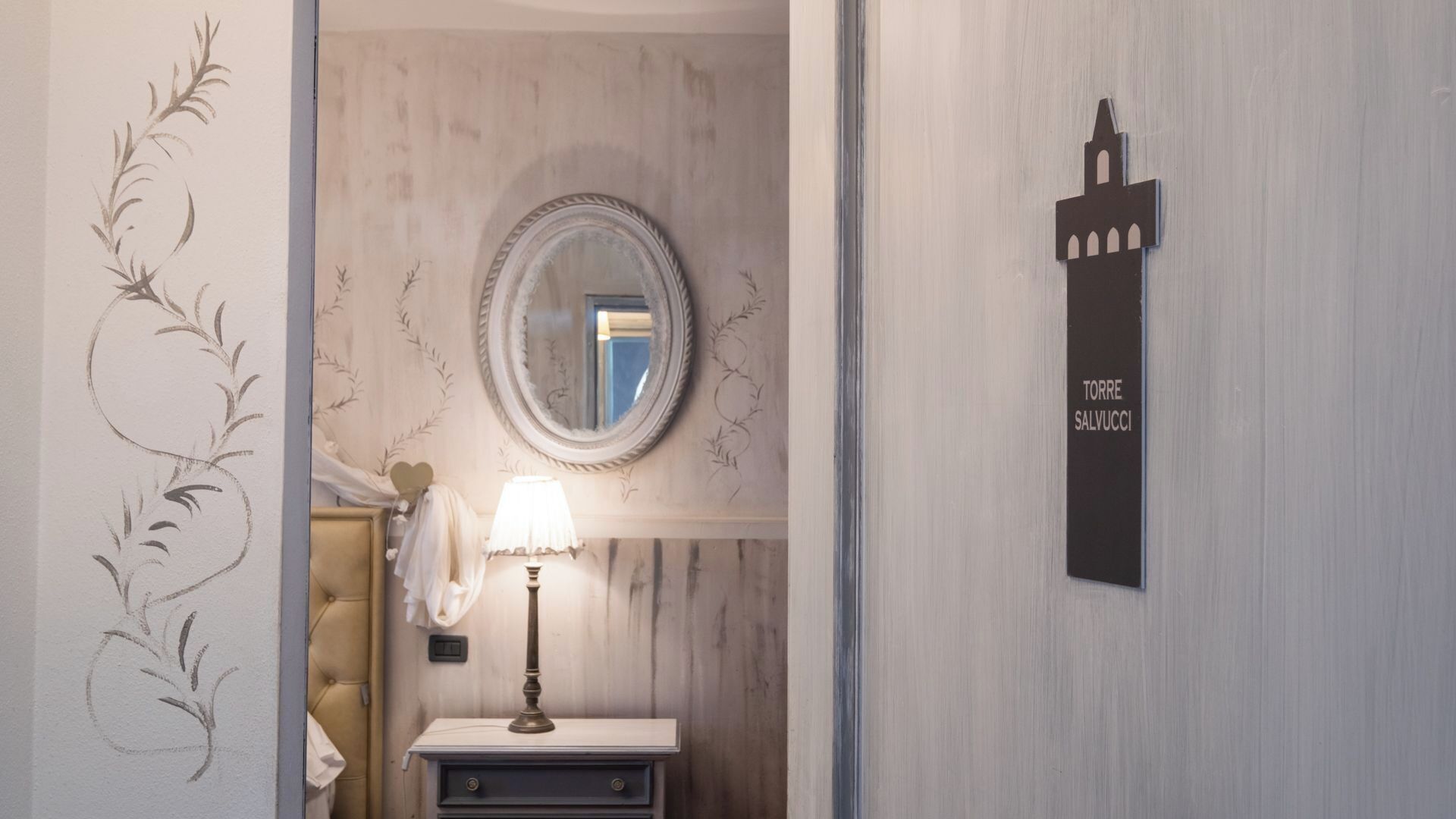 Un baño con espejo, un cartel en la pared que dice "TORRE SALVUCCI" y un diseño decorativo en la pared.