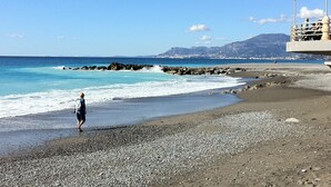 Una platja de pedres i una persona caminant.