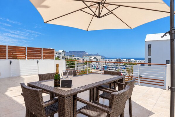 An outdoor patio with wicker furniture, a table, and a bottle of champagne.