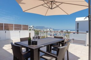 A terrace with a table and chairs, a bottle of champagne, and a menu sign.