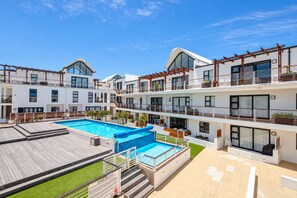 A multi-story hotel with a swimming pool, balconies, and a terrace area.