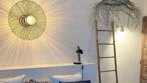 A bedroom with a bed, a ceiling fan, a wall-mounted light, and a ladder.