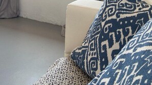 A room with a window, a ladder, and patterned cushions.