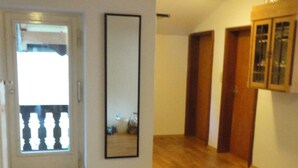 Una habitación vacía con suelo de madera, una puerta que da a un balcón y un espejo grande en la pared.