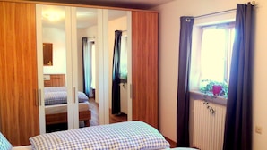 Un dormitorio con dos camas, un armario de madera y una ventana con cortinas.