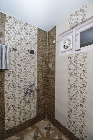 A bathroom with patterned walls, a shower, and a window with a decorative fan.